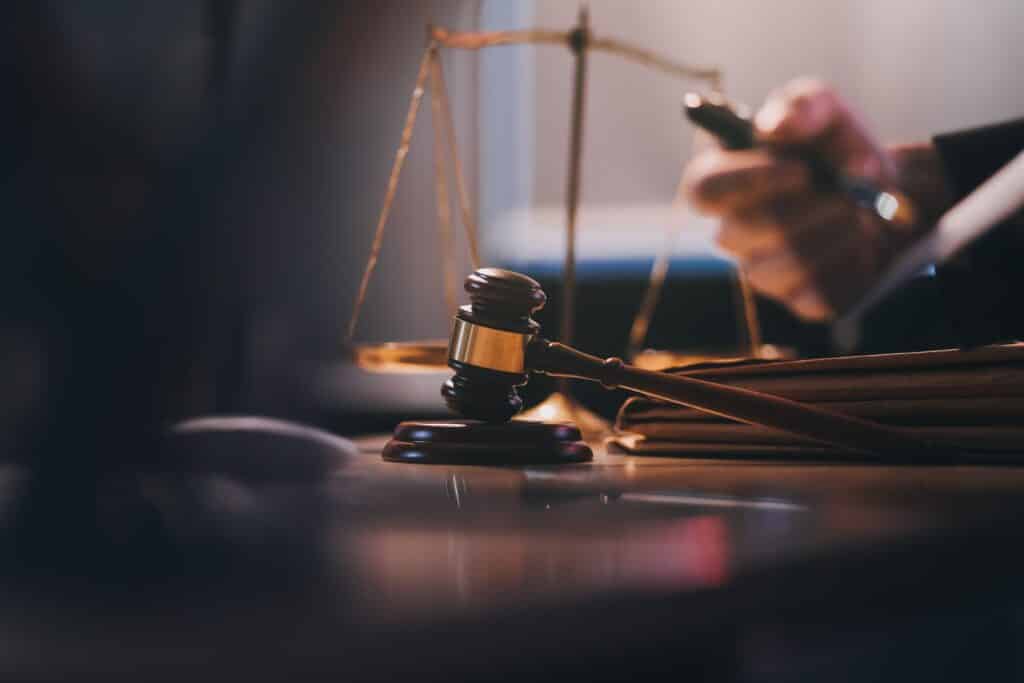 A wooden judge’s gavel resting on a desk next to legal documents and a blurred scale of justice, relevant to a criminal defense attorney.
